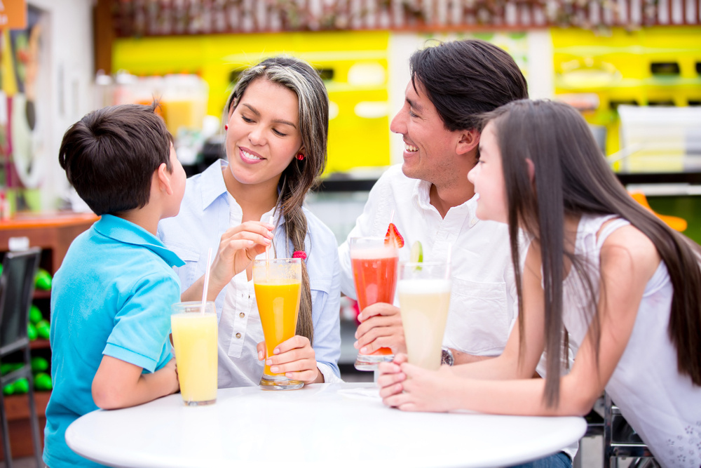 Happy family at a cafeteria drinking juices